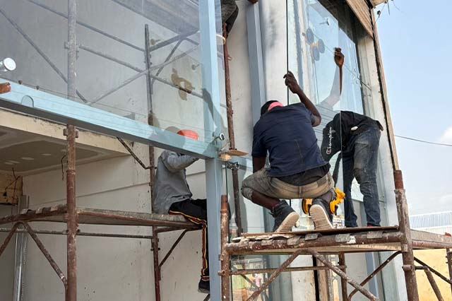 Installers working on a glass curtain wall from scaffolding